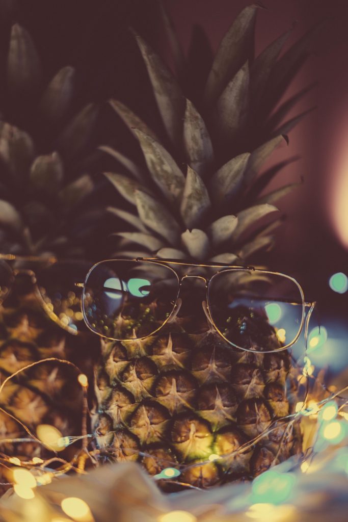 A pineapple with a glasses and fairy lights.