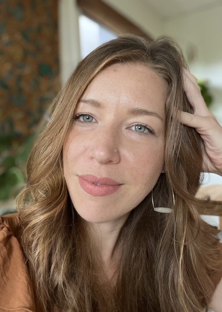 a woman with long hair and a hand on her head - Julia Hollenberg | Food and Body Therapy in Seattle & Online